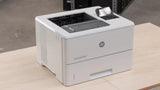 HP LaserJet Enterprise M507 printer on wooden table, white office laser printer for business use